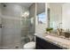 Modern bathroom featuring a tiled shower with a glass door, granite countertop, and garden window at 2821 E Cashman Dr, Phoenix, AZ 85050