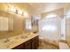 Well-lit bathroom with double sinks, dark wood vanity, updated fixtures, tile floors and shower-tub combo at 3538 E Squawbush Pl, Phoenix, AZ 85044