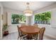 Bright dining room features a wooden table set illuminated by modern lighting and views of lush greenery through large windows at 39 E Tam Oshanter Dr, Phoenix, AZ 85022