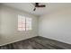 This bedroom features a dark ceiling fan, wood floors, neutral colored walls, and a sunlit window at 5302 E Van Buren St # 3040, Phoenix, AZ 85008