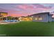 Expansive backyard featuring a pool, ample seating, and lush artificial turf under a colorful sunset sky at 7130 E Navarro Way, Scottsdale, AZ 85266