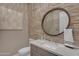 Elegant powder bathroom with stone accent wall, unique mirror, and a stylish sink vanity with decorative wall art at 7130 E Navarro Way, Scottsdale, AZ 85266