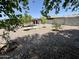 A roomy backyard featuring gravel, mature trees, a garden, and a covered patio seating area at 7551 W Darrel Rd, Laveen, AZ 85339
