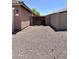 Side view of a single-story house featuring a two-car garage and gravel landscaping and a fenced side yard at 7551 W Darrel Rd, Laveen, AZ 85339