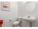 Powder room showcasing a pedestal sink, round mirror, toilet, and decorative wall art at 7829 W Warner St, Phoenix, AZ 85043