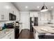 This kitchen features granite countertops, stainless steel appliances, sleek dark hardwood floors and modern white cabinets at 7829 W Warner St, Phoenix, AZ 85043