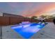 Beautiful pool highlighted by a stacked stone waterfall, and surrounded by concrete and desert landscaping at 7829 W Warner St, Phoenix, AZ 85043
