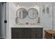 Modern bathroom featuring double sinks, round mirrors, and a glass-enclosed shower at 8021 N 16Th Dr, Phoenix, AZ 85021