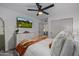 Well-lit bedroom showcasing ceiling fan, TV, closet doors, and stylish white bedding at 8021 N 16Th Dr, Phoenix, AZ 85021