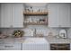 Charming kitchen features a farmhouse sink, open shelving, and marble countertops at 8021 N 16Th Dr, Phoenix, AZ 85021