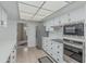 Kitchen featuring modern stainless steel appliances, white cabinets, and tile flooring at 9606 W Long Hills Dr, Sun City, AZ 85351
