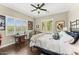 Bright bedroom featuring wood floors, plantation shutters, ceiling fan, and eclectic decor at 9936 E Winter Sun Dr, Scottsdale, AZ 85262