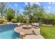 Resort-style backyard featuring a fire pit with stone accents and lush landscaping at 9936 E Winter Sun Dr, Scottsdale, AZ 85262
