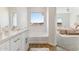 Bright, spacious bathroom with a soaking tub, white vanity, and large window with view at 11203 E Crescent Ave, Mesa, AZ 85208
