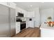 Well-lit modern kitchen featuring stainless steel appliances and sleek white cabinetry against wood flooring at 11203 E Crescent Ave, Mesa, AZ 85208