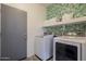 Laundry room featuring a washer and dryer, open shelving, and stylish wallpaper at 13140 W Rowel Rd, Peoria, AZ 85383