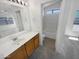 Well-lit bathroom with a wooden vanity, tile flooring, and a separate tub and shower at 14065 W Cornerstone Trl, Surprise, AZ 85374