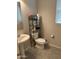 A functional half-bathroom with a toilet, pedestal sink, and metal shelving unit at 15301 W Moreland St, Goodyear, AZ 85338