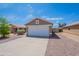 Tan home exterior with a two car garage, low maintenance landscaping, and a concrete driveway at 15725 W Lundberg St, Surprise, AZ 85374