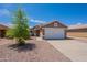 Exterior of tan home with two-car garage, desert landscaping, concrete driveway and security door at 15725 W Lundberg St, Surprise, AZ 85374
