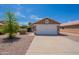 Exterior of tan home with two-car garage, desert landscaping, and concrete driveway at 15725 W Lundberg St, Surprise, AZ 85374