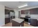 A kitchen showcasing an island, tile flooring, stainless steel appliances, and dark cabinetry at 15725 W Lundberg St, Surprise, AZ 85374