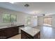 A well-lit kitchen featuring gray countertops, dark cabinets, tile flooring, and backyard views at 15725 W Lundberg St, Surprise, AZ 85374