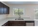 A kitchen with gray countertops, a stainless steel sink, stainless steel appliances, and dark cabinets at 15725 W Lundberg St, Surprise, AZ 85374