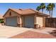 Exterior shot of a three-car garage with desert landscaping and mature palm trees in the background at 1625 E Daisy St, Casa Grande, AZ 85122