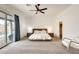 Bright main bedroom featuring a ceiling fan, plush carpet, stylish wooden bed frame and walk-in closet at 16398 N Oachs Dr, Surprise, AZ 85374
