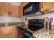 Close up of the kitchen with wooden cabinets, granite countertops, and black appliances at 1721 E Cielo Grande Ave, Phoenix, AZ 85024