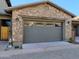 Stone-accented garage with a gray door featuring decorative windows and exterior lighting fixtures at 18507 N 94Th St, Scottsdale, AZ 85255