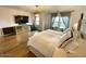Spacious primary bedroom features hardwood floors, chandelier, tv, decorative curtains, and neutral decor at 18507 N 94Th St, Scottsdale, AZ 85255