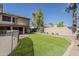 Large backyard featuring artificial grass, desert landscaping, and covered patio at 1927 E Ranch Rd, Tempe, AZ 85284