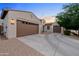 Beautiful home featuring a three-car garage, concrete driveway, and desert landscaping with a view of the sunset at 19905 E Apricot Ln, Queen Creek, AZ 85142