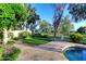 Backyard with lush green lawn, tiled patio, partial pool view, and manicured landscaping at 2041 W Hemlock Way, Chandler, AZ 85248