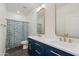 Bright bathroom with dual sinks, navy blue cabinets, gold hardware, and tub with floral shower curtain at 20713 N 91St Dr, Peoria, AZ 85382