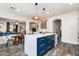 Kitchen island with white countertop, blue cabinets and pendant lighting open to living spaces at 20713 N 91St Dr, Peoria, AZ 85382