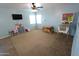 Living room features neutral carpet and a ceiling fan with views of backyard through bright windows at 2434 E San Manuel Rd, San Tan Valley, AZ 85143