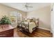Cozy bedroom featuring hardwood floors, a wrought iron bed frame, and a window with plantation shutters at 27953 N 111Th Way, Scottsdale, AZ 85262