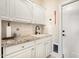 Practical laundry space features granite counters, sleek white cabinetry and a pet door at 27953 N 111Th Way, Scottsdale, AZ 85262