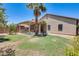 Landscaped backyard featuring covered patio with built-in BBQ, palm trees and green grass at 38125 W Santa Clara Ave, Maricopa, AZ 85138