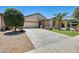 Charming single-story home featuring desert landscaping, green lawn, and a spacious two-car garage at 38125 W Santa Clara Ave, Maricopa, AZ 85138