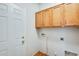 This laundry room features wood cabinets, a white door, and washer/dryer hookups at 38125 W Santa Clara Ave, Maricopa, AZ 85138