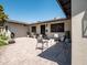 Brick patio with a seating area, lush green lawn, and black framed windows at 5919 S Newberry Rd, Tempe, AZ 85283