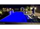 Night shot of a backyard pool featuring lounge chairs, an umbrella, and a decorative tiled water feature at 5919 S Newberry Rd, Tempe, AZ 85283