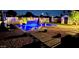 Backyard pool at night showcasing tiled water feature, umbrellas, in-pool lounge chairs and decorative pavers at 5919 S Newberry Rd, Tempe, AZ 85283