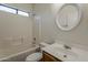 Standard bathroom with a tub-shower combo, white tile surround, and a round mirror above the sink at 8733 W Laurel Ln, Peoria, AZ 85345