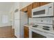 Kitchen featuring white appliances, wood cabinets, and access to living area at 8733 W Laurel Ln, Peoria, AZ 85345
