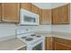Kitchen featuring classic oak cabinetry, tile floors, and white appliances at 8733 W Laurel Ln, Peoria, AZ 85345
